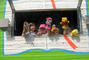 Kids in window of Puppet Wagon with hand puppets