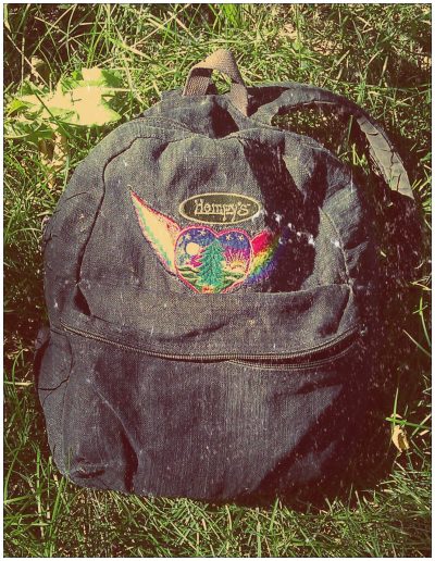 Black backpack with a rainbow heart patch packed with supplies for a day out with kids