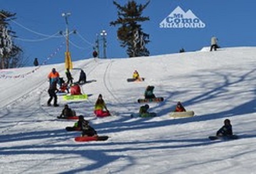 Youth with snowboards sitting on Como Park Ski Hill taking part in lessons.