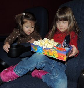 Two girls sharing popcorn during a movie at the Mall of America in Bloomington Minnesota