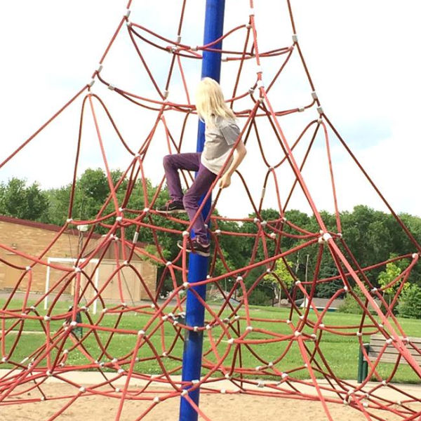 Girl climbing net web at Waite Park in Minneapolis, Minnesota