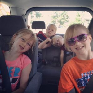 Four kids packed into a mini van ready for a roadtrip