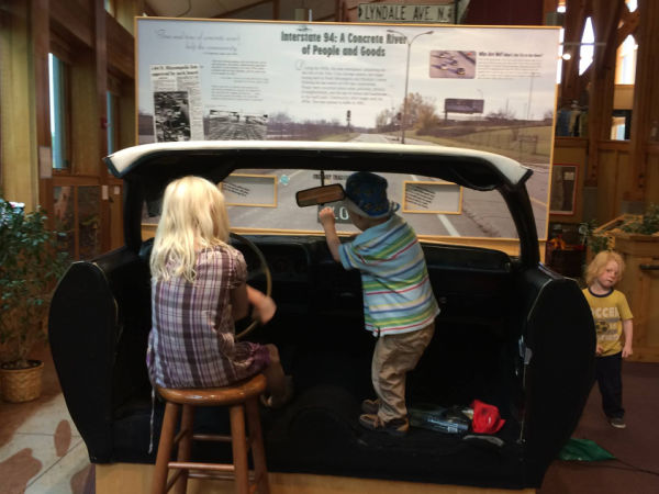 Kids playing in front half of an old car and learing about Hwy 94 at Carl Kroening Interpretive Center in Minneapolis, MN