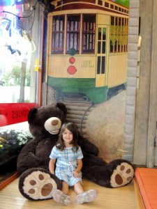 Girl playing with giant bear at the Great Harvest in Linden Hills neighborhood, Minneapolis, MN