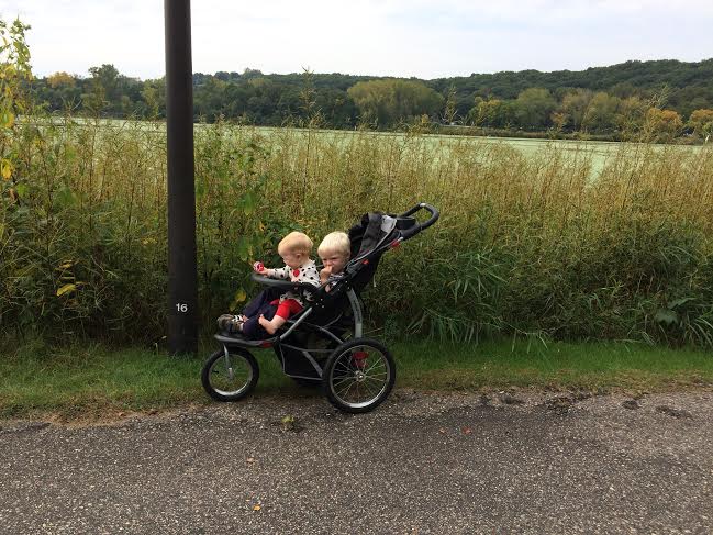 Two small kids in a jogger stroller during a walk around Normandale Lake Park in Bloomington, Minnesota