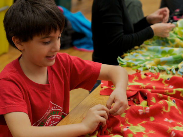 Boy tying a no-sew blamket to donate to Project Linus