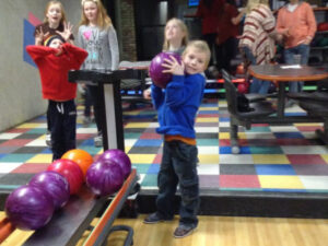 Boy lifting heaving bowling ball at Twin Cities Bowling Alley