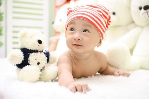 baby on a blanket with stuffed animals