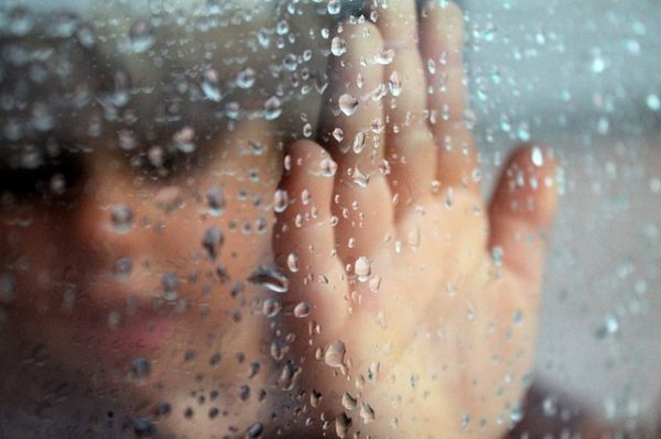 Child looking through window on a rainy day