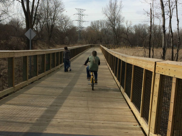 Pedestrian and Biker using the boardwalk trail at Long Lake Regional Park in New Brighton, Minnesota