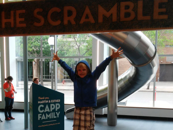 Boy cheering after being the first kid to ever go down The Scramble at Minnesota Children's Museum in St. Paul, Minnesota