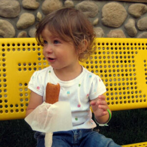 Toddler girl eating a corn dog at the Minnesota State Fair