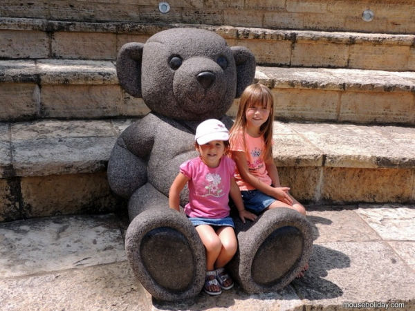 Little girl sitting on giant teddybear lap at Teddybear Park in Stillwater, Minnesota