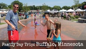 Family playing in public splash pad in Buffalo, Minnesota. Text: Family Day Trip: Buffalo, Minnesota.