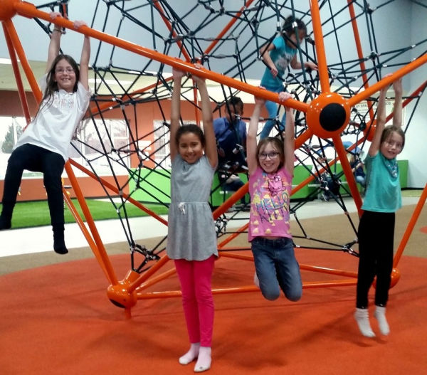 A group of kids hanging from the climbing web at Good Times Park in Eagan Minnesota