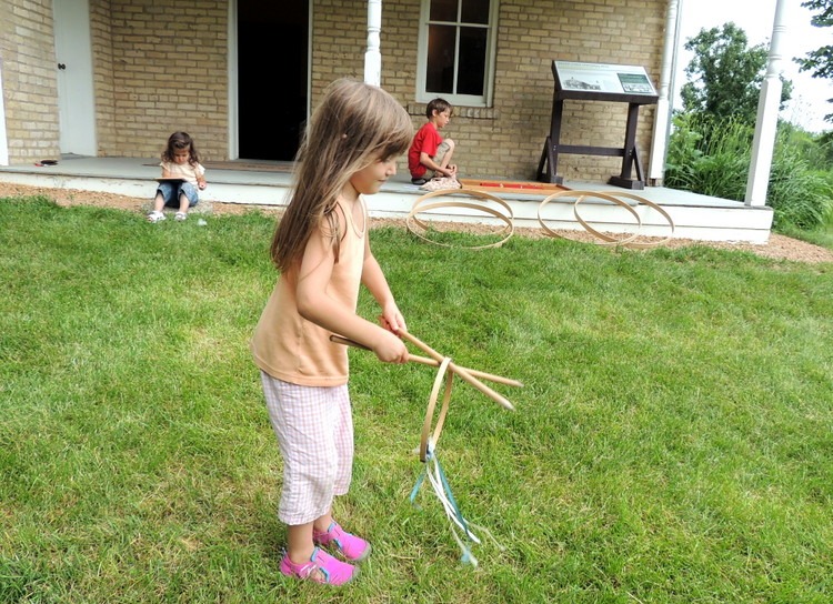 Kids trying out old-fashioned games at Historic Grimm Farmhouse in Victoria, Minnesota