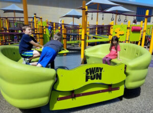 Kids playing on the accessible Sway Fun at Madison's Place Playground in Woodbury, Minnesota