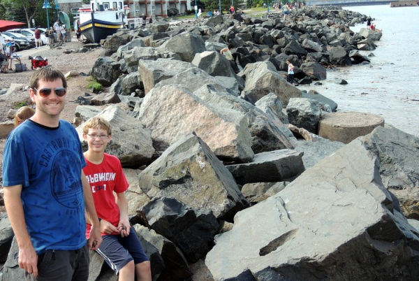Father and son on the rocks lining the shore of Lake Superior in Canal Park in Duluth Minnesota