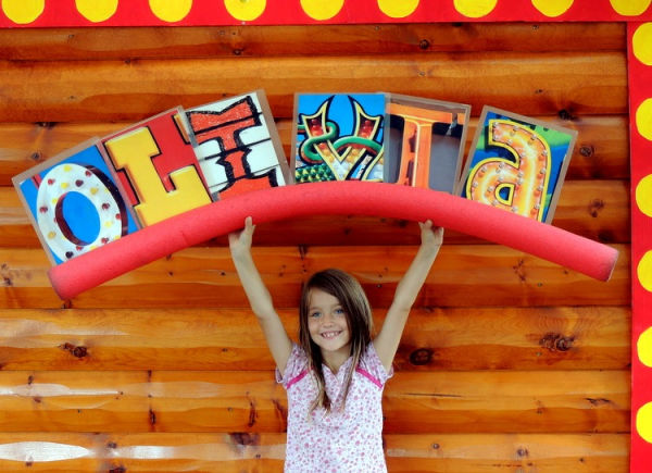 Girl showing her 'OLIVIA" name poster at the Alphabet Forest attraction at the Minnesota State Fair