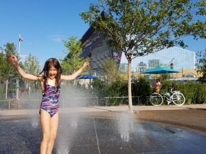 Girl splashing in a spray fountain at The Commons in Downtown Minneapolis