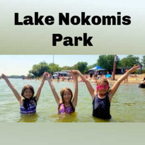 three swimmers joining hands in the air while standing in Lake Nokomis in Minneapolis, Minnesota