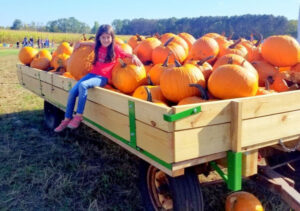 Girl in a wagon full of pumpkins at Waldoch Farm in Lino Lakes Minnesota