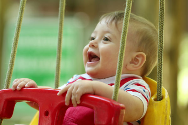 Baby laughing in park swing