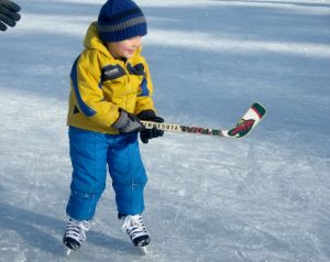 Small boy playing hockey on outdoor rink