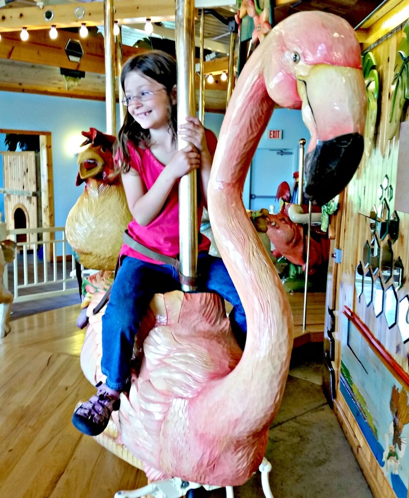 Girl riding flamingo merry go round at Lark Toy Store in Kellogg, Minnesota