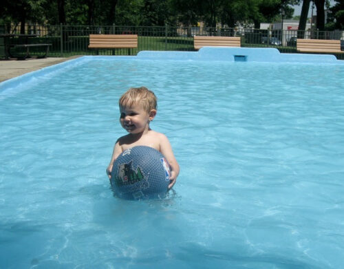 Toddler playing with a Timberwolves playground ball in the wading pool at Van Cleve Park in Minneapolis, Minnesota