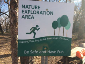 Green and white sign "Nature Exploration Area. Explore, Play, Dig, Rearrange, Discover... Be Safe and Have Fun" found at Mississippi Gateway Regional Park in Brooklyn Park, Minnesota