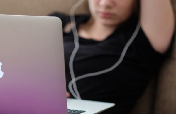 Teenager in front of a laptop with earbuds in.