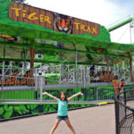 Excited girl in front of the Tiger Trax roller coaster at Como Town Amusement Park in Saint Paul Minnesota