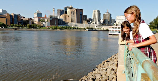 Two girls on shoreline of the Mississippi River with skyline in background at Harriet Island Park in Saint Paul Minnesota