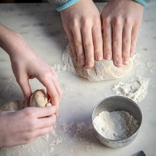 Kids hands kneading whole wheat pizza dough