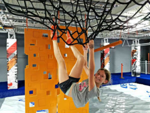 Girl hanging from climbing nets at Sky Zone Trampoline Park
