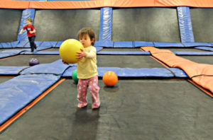 Toddler playing with a big yellow ball at Sky Zone Trampoline Park