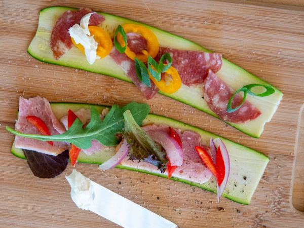 Two slices of zucchini with roll-up toppings next to a knife on a cutting board - Back to School Lunch Rollups
