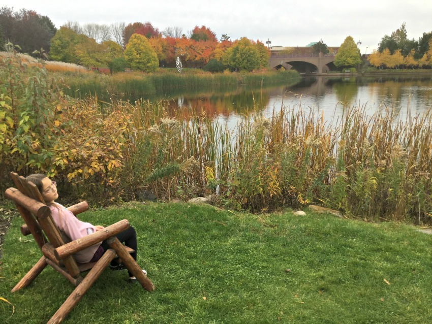 Girl resting in an Adirondack chair by the pond in Centennial Lakes Park, Edina, Minnesota