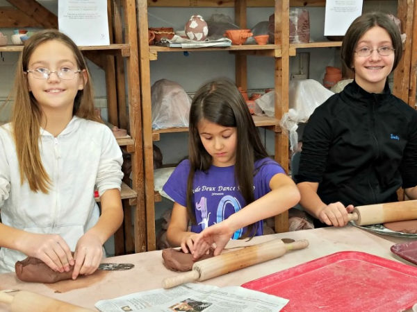 Three girls rolling out clay creations at Northern Clay Center in Minneapolis, MN