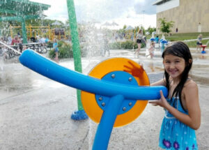 girl shooting water sprayer at Madison's Place Playground Splash Pad in Woodbury, Minnesota