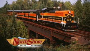 Great Northern Engine #192 pulling orange and black train across a bridge. Text: "North Shore Scenic Railroad."