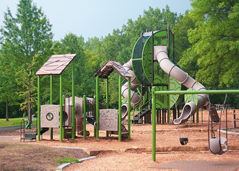 Battle Creek Regional Park Main Playground includes swirly slides, zip line swings, a fort building area, logs to balance on and a play stream