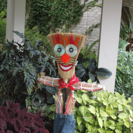 Scarecrow made from broom with red nose, a big smile and a bowtie.