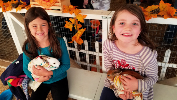 Two girls holding rabbits at Twin Cities Spring Festival in Brooklyn Park, MN