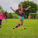 Girl leaping over hurdle at AKASport Camp