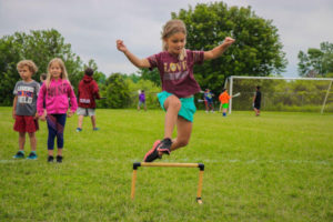Girl leaping over hurdle at AKASport Camp