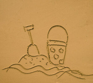 A drawing in sand of a bucket and shovel sandcastle