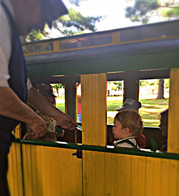 Conductor taking kids tickets on miniature train at Carson Park in Eau Claire WI