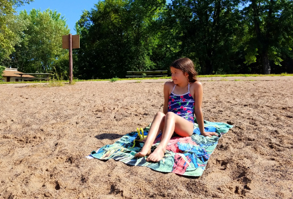 Girl sitting on beach at William O'Brien State Park in St. Croix, Minnesota